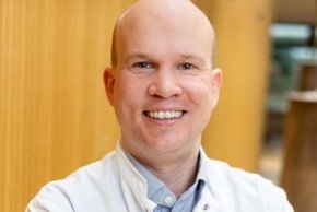 Dr. Raban Graf von Soden-Fraunhofen, Facharzt für Innere Medizin und Rheumatologie am MVZ Klinikum Straubing, erläutert das neue Angebot der Früharthritis-Sprechstunde. (© Johannes Lehner) Ein Herr mit wenig Haaren im Arztkittel und hellblauem Hemd, lachend
