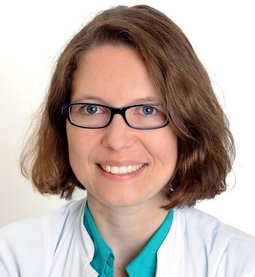Franziska Grumbeck (© Fotowerbung Bernhard) Dame mit halblangen braunen Haaren und Brille, türkiser Bluse, Kittel, läschelnd